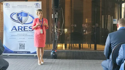 Participantă în ținută roz, adresându-se publicului la Forumul ARES